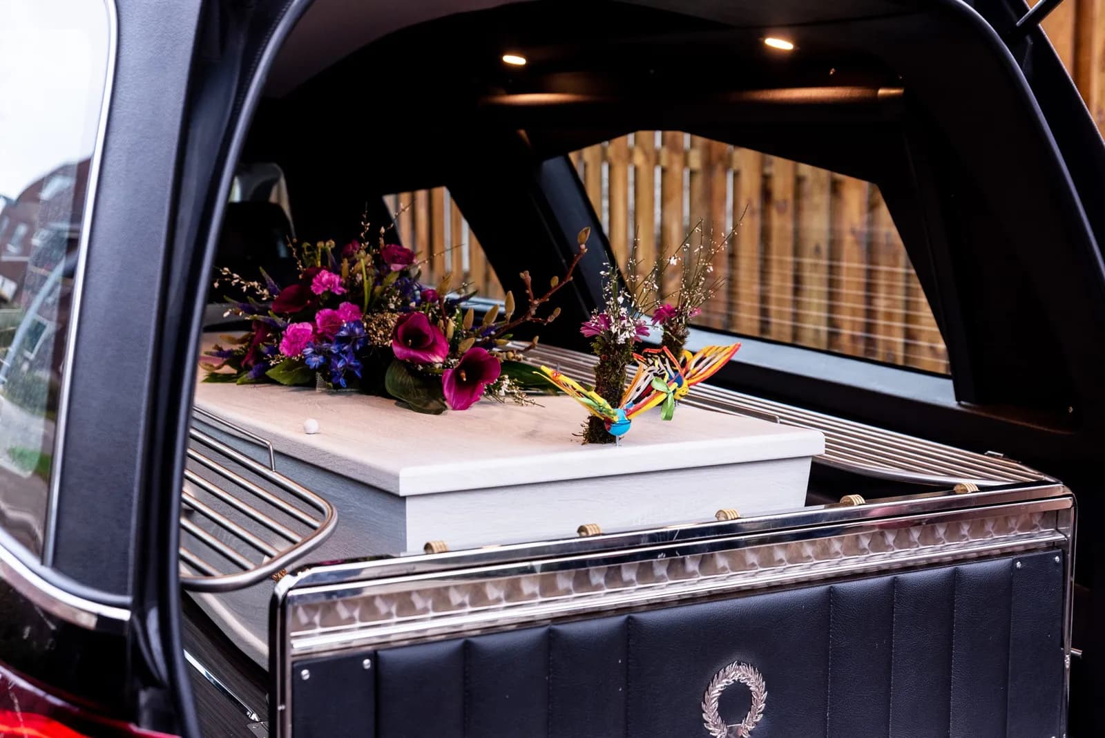 Wit kinderkistje met bloemen in de rouwauto